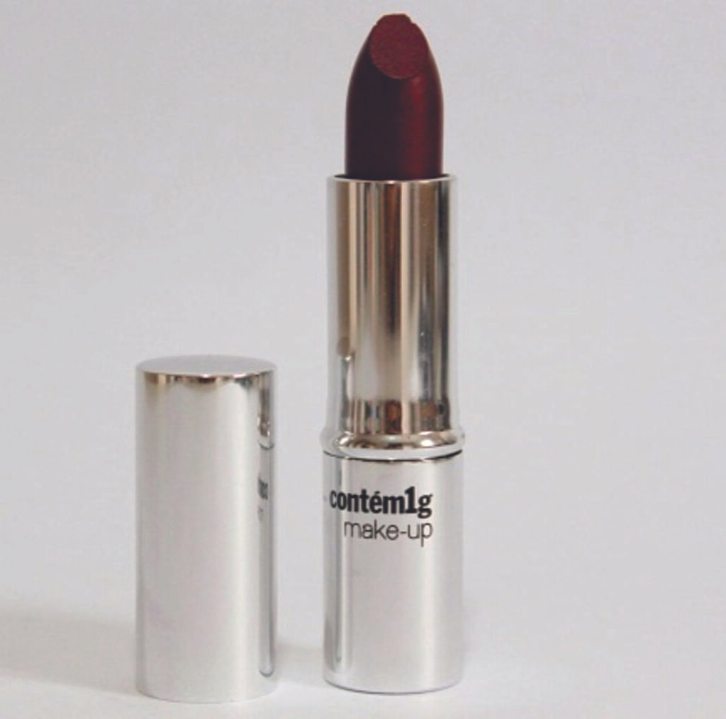 Tubo de batom prateado com a marca “contém1g make-up” e batom vermelho escuro exposto.